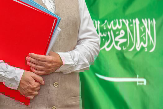 Woman's hands holding documents against Saudi Arabia flag background. Education abroad photo