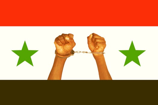 Hands locked in handcuffs. The Syrian flag. photo