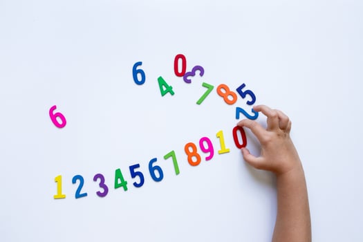 Child hand arranging colorful magnetic numbers on white background photo