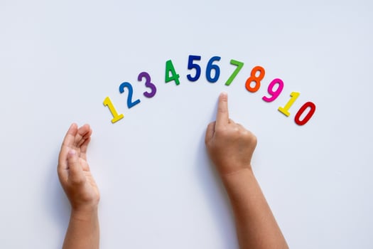 Child hands pointing at colorful wooden numbers on white background photo