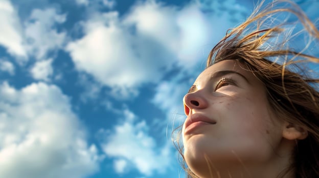 Person looking up to blue cloudy sky in sunlight wind photo