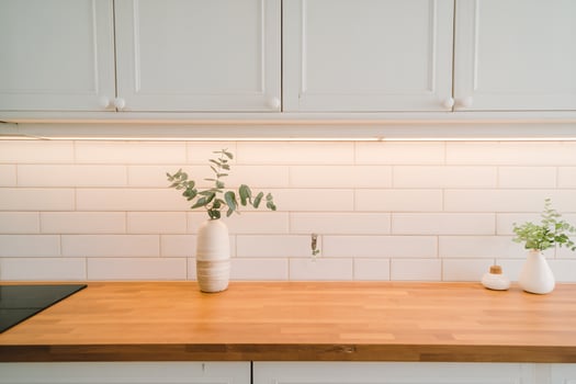 A modern kitchen with a wooden counter, featuring minimalist decor and fresh greenery. photo