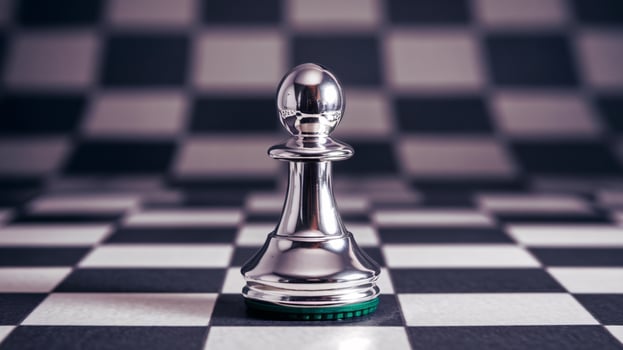 A close-up of a shiny silver chess pawn on a black and white checkered board. photo