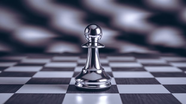 A close-up view of a silver chess pawn on a classic black and white chessboard. photo