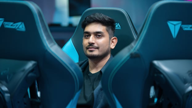 Young South Asian male gamer sitting confidently between gaming chairs. photo