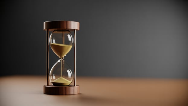 A close-up of a decorative hourglass on a wooden surface, symbolizing the passage of time and patience. photo