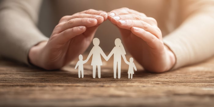 The hands providing protection for a loving family silhouette cutout. photo