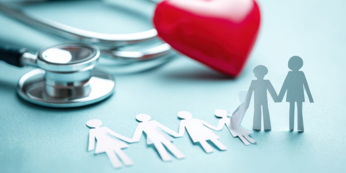 The paper cutout family holding hands with a stethoscope and heart. photo