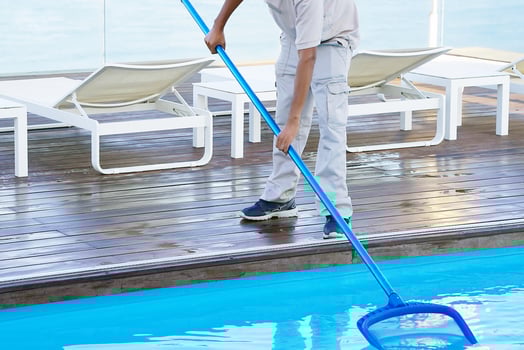 Hotel man staff worker cleaning the pool in the morning photo