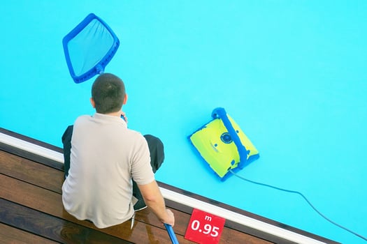 Man holds pool cleaning net at pool hotel photo