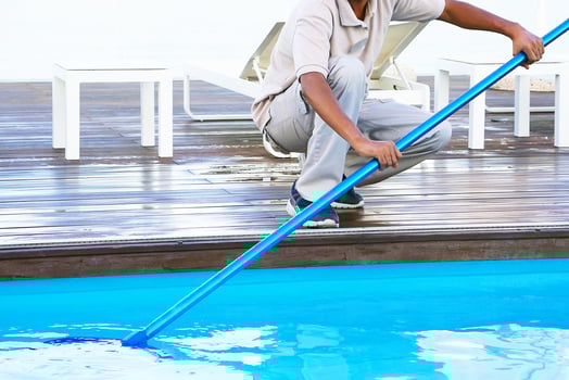 Black staff worker cleaning the pool with pool cleaning net photo