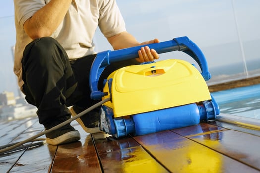 Caucasian man holds a pool cleaning robot in pool photo