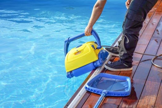 Eoropean staff worker cleaning the pool and holds a pool cleaning robot photo