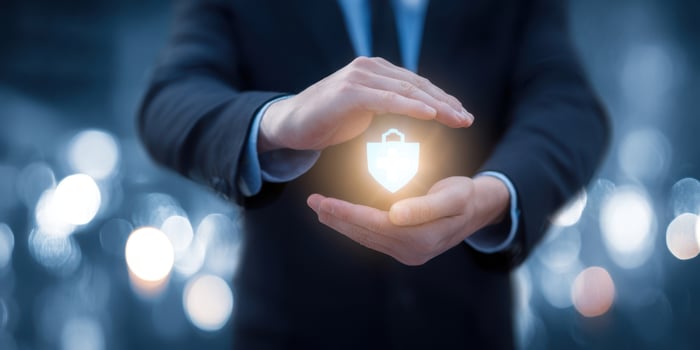 The hands protecting a glowing security shield in a corporate setting. photo