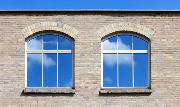 Blue sky reflected in arched windows of a brick building photo