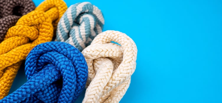 Colorful knotted ropes on blue background. Nautical theme. Craft supplies photo