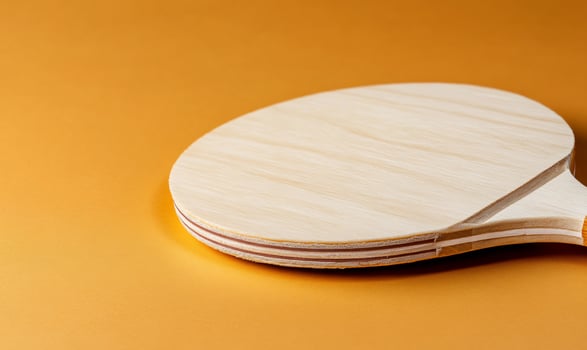Table tennis paddle, orange background, closeup photo