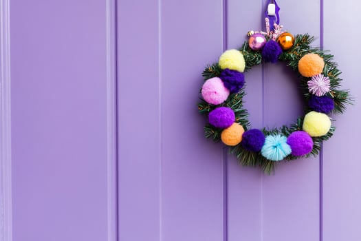 Colorful pompom Christmas wreath on purple door photo