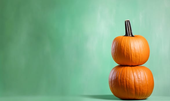 Two pumpkins stacked, green background, autumn, fall decor photo