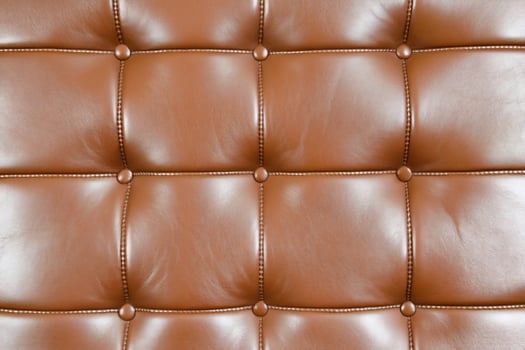 Closeup of a luxurious brown leather sofa with tufted design photo