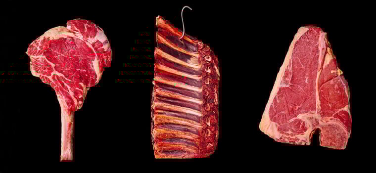 Different cuts of raw beef arranged against a black background photo