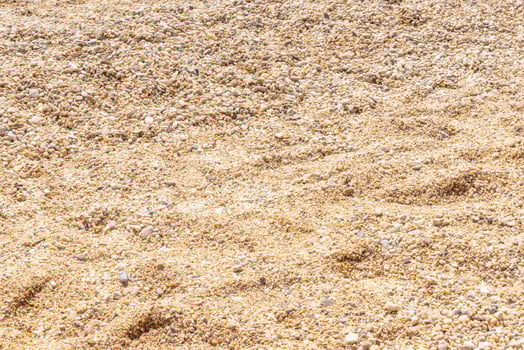 Close-up of fine beach pebbles in shades of beige and cream under bright sunlight photo