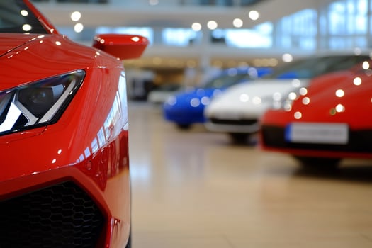Closeup of a vibrant red sports car in a modern showroom with blurred cars photo
