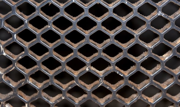 Closeup of a rusted metal honeycomb grille with dirt accumulation photo