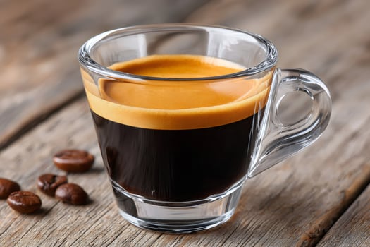 Glass cup of hot espresso coffee with beans on rustic wooden table photo