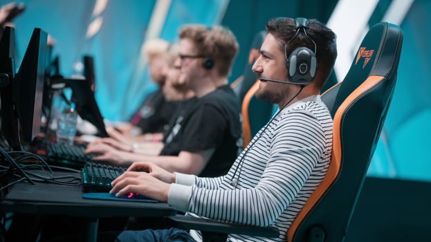 A focused male gamer concentrates during a competitive esports match, wearing a headset and seated at his gaming station. photo