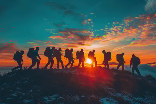 Silhouette hiker group ascending mountain ridge at colorful sunset photo