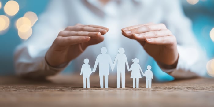 The hands protecting a paper family symbolizing love and unity photo