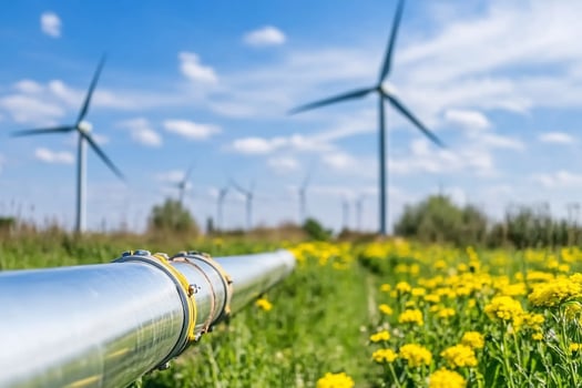 Wind Turbines in a Field of Flowers with a Metal Pipe in the Foreground photo