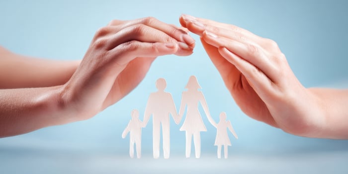 The hands symbolically protect and unite a paper family representation. photo