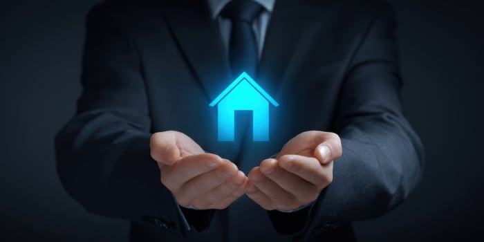 The businessman holding a glowing house symbol in his hands for protection. photo