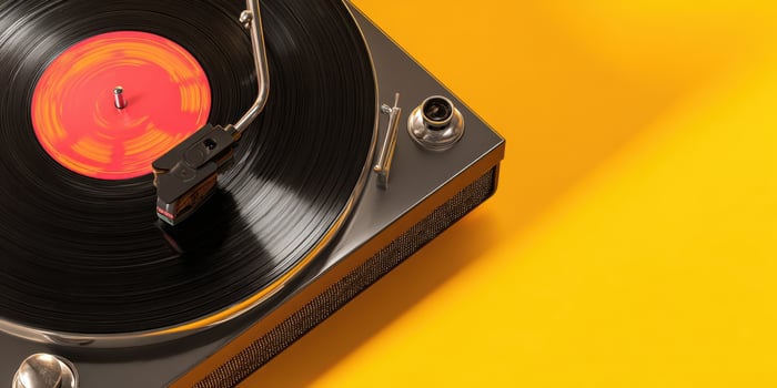 The vintage turntable spinning a classic vinyl record against a yellow backdrop. photo