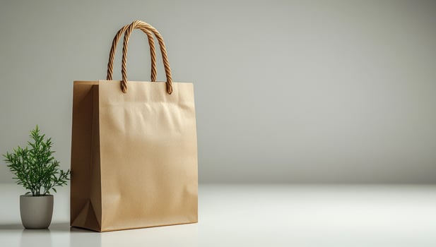 Paper shopping bag with plant on gray background studio shot photo