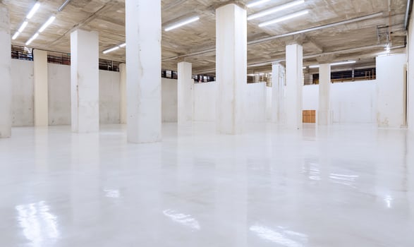 Empty warehouse interior, bright lighting, concrete columns, reflective floor, industrial background photo