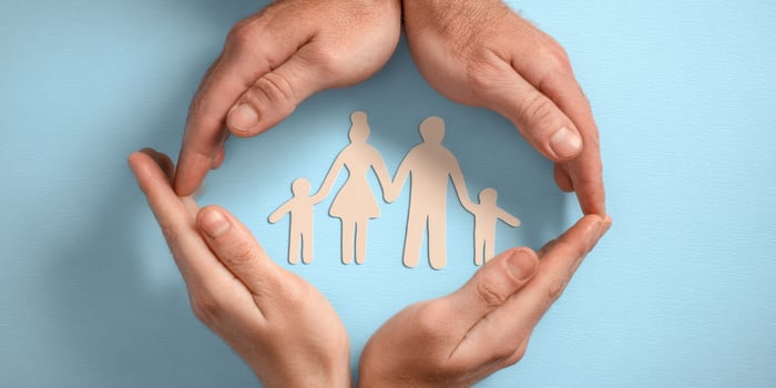 The Hands Protecting a Family Silhouette on a Soft Blue Background photo