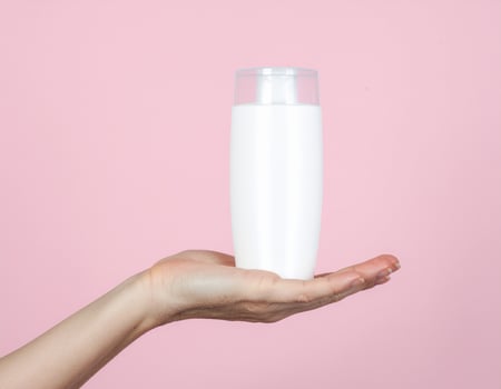 Woman's hand holding white cosmetic bottle photo