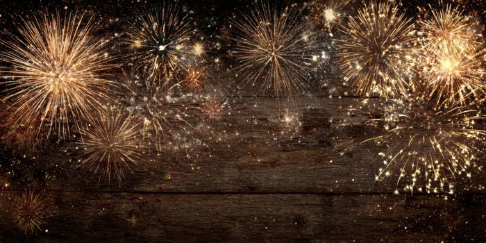 The vibrant fireworks illuminating the night sky over a rustic wooden background. photo