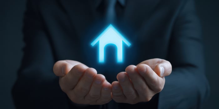 The Businessman Holding a Digital Home Icon in His Hands photo
