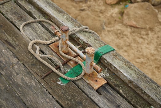 A Rusty Metal Clamping Device Resting on a WellWorn Wooden Surface in a Scenic Setting photo