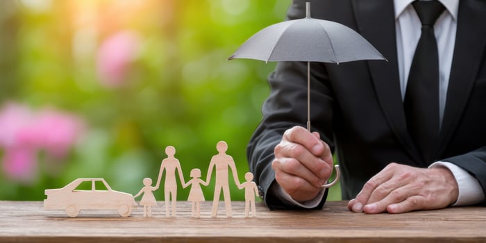 The businessman holding an umbrella over a family and car figurines photo