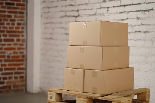 Cardboard boxes stacked on pallet, brick wall background storage, logistics photo