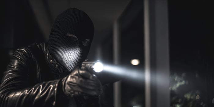 The masked figure aiming a flashlight in a tense nighttime scene photo