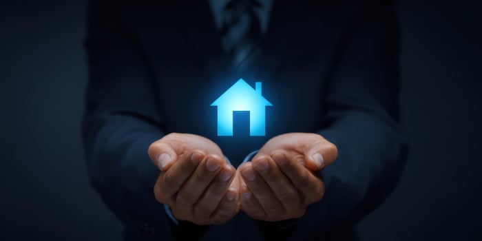 The hands holding a glowing home icon symbolizing secure property investment. photo