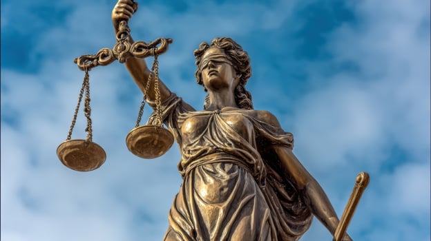 The bronze statue of Lady Justice holding scales against a blue sky. photo