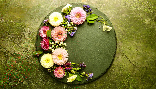 Vibrant spring flowers artfully arranged on a dark slate circle, evoking natural beauty and freshness. photo