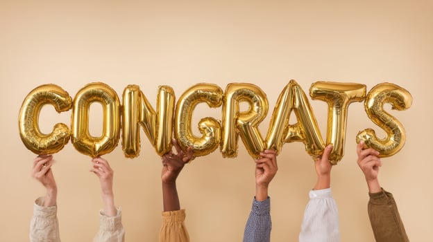 The golden balloons spelling congrats held by joyful hands. photo